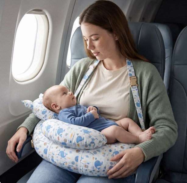 Maman assise dans un avion avec son bébé sur le coussin Nolia bleu